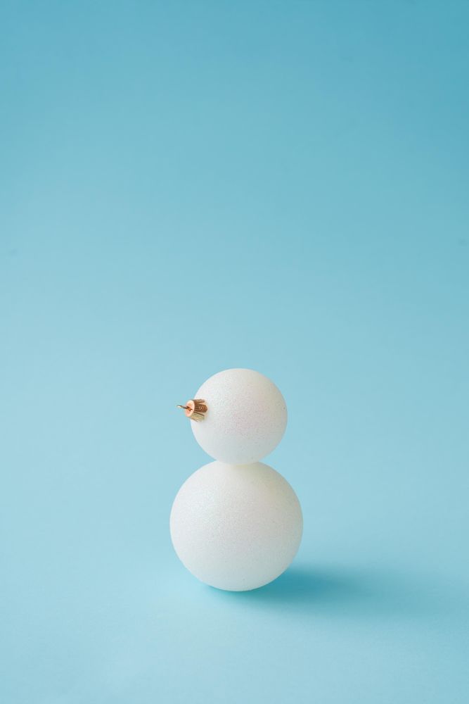 Snowman made of Christmas bauble decoration on pastel blue background