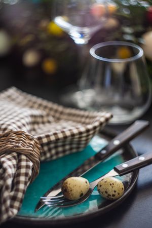 Close up of Easter table setting with delicate spotted eggs on ceramic teal plate