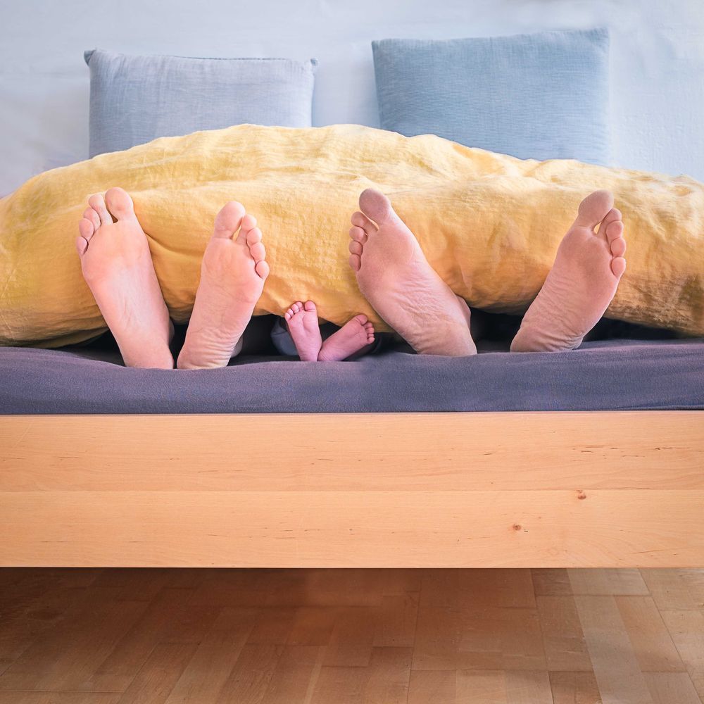 Father and mother and child legs out of bedsheets