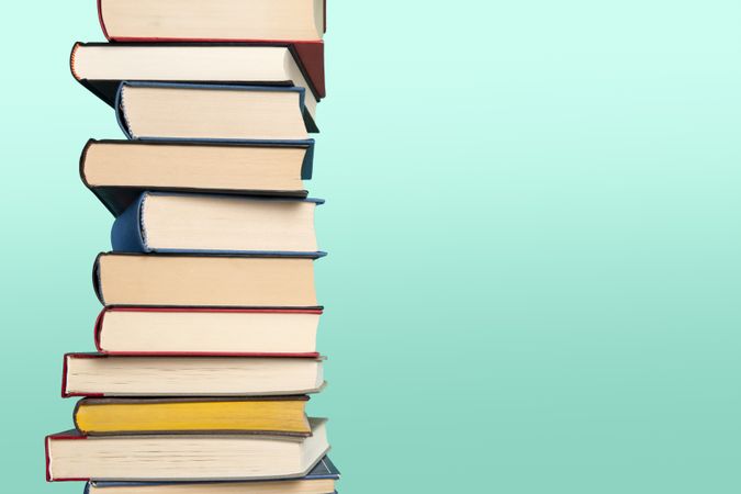 Pile of books stacked on a blue background with space for copy