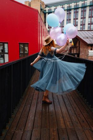 Woman dancing in streets with balloons