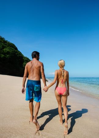 Love couple walking along the tropical beach
