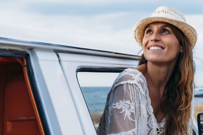 Smiling woman in hat in front seat of car opening door