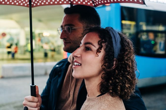 Happy couple with umbrella on wet street