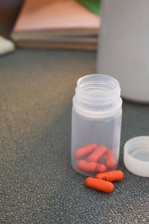 Red medical pills in container on counter