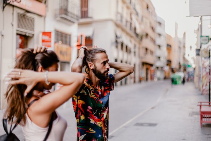 Couple making ponytails on street alley