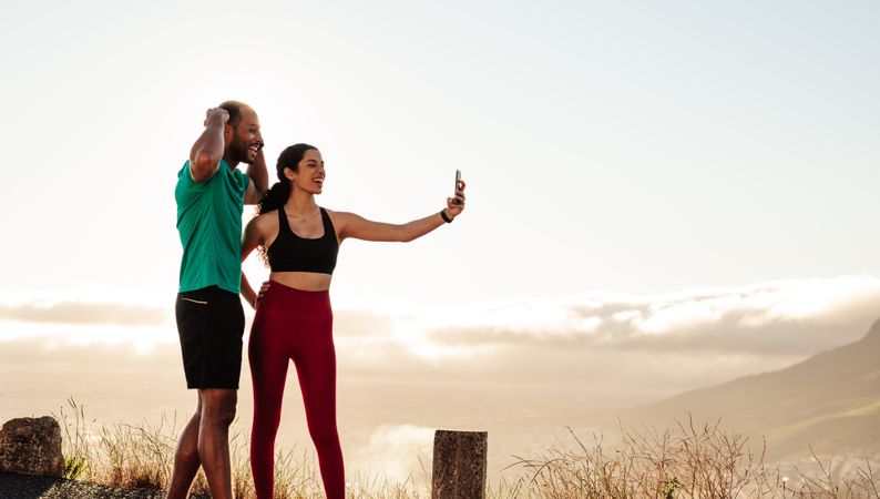 Fitness couple standing outdoors taking a selfie after workout