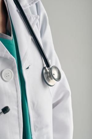Crop physician in medical robe with stethoscope