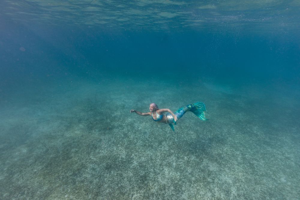 Blond fairytale female mermaid swimming underwater