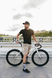 Cheerful man with bicycle standing on footbridge