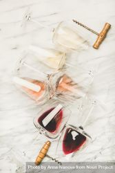 Glasses of wine laying on marble background with corkscrew begLN5