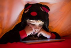 Boy using tablet under blanket