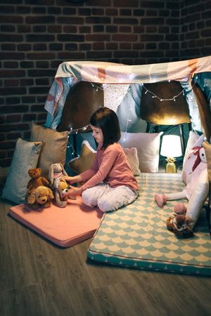 Girl playing with stuffed animals in a teepee