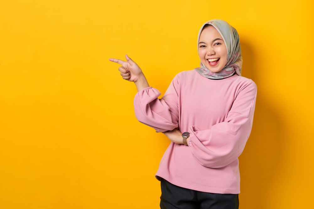 Laughing Muslim woman in scarf pointing to her side