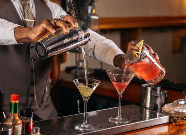 Black bartender preparing a cocktail in a traditional cocktail bar
