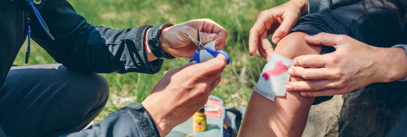 Man healing knee to woman who has been injured trekking