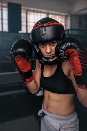 Female boxer in head gear & gloves standing in the ring
