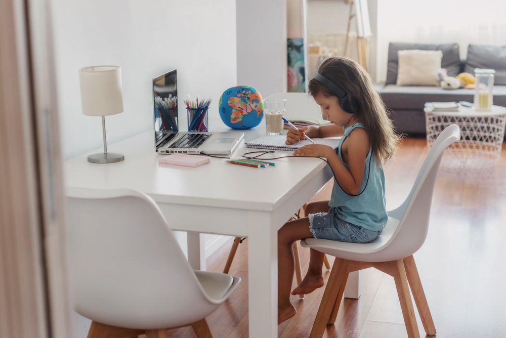 Young girl wearing headphones and using laptop at home