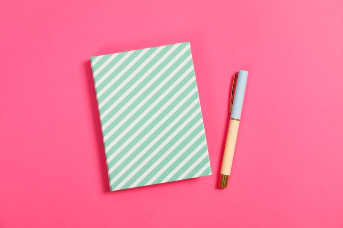 Copybook and pen on pink background, space for text