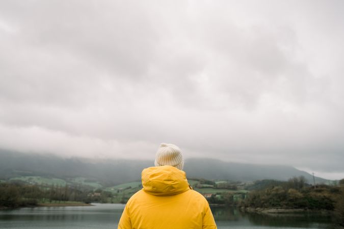 Person in coat with camera near lake