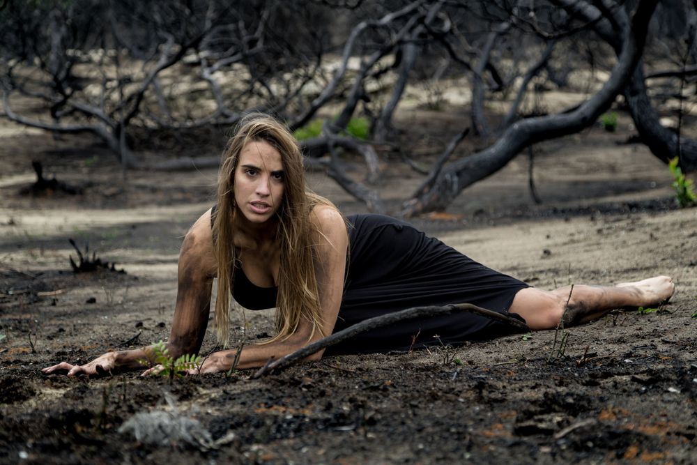 Woman posing on ground near dry trees