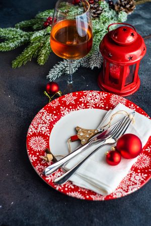Holiday table setting on red plates with lantern and glass of wine