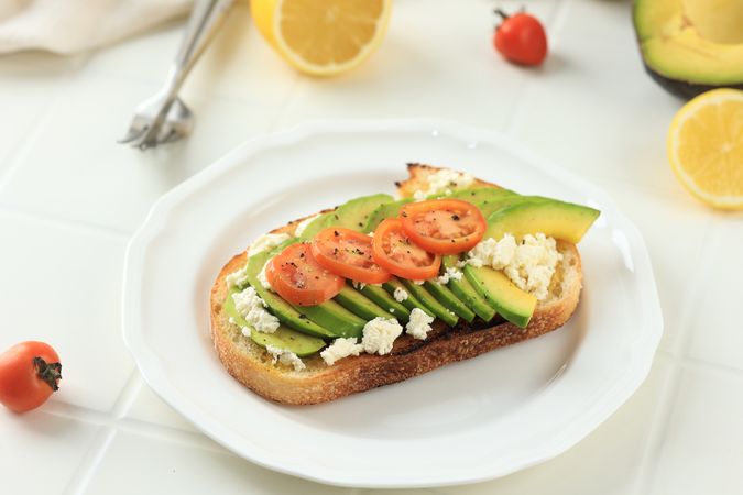 Avocado Sourdough Toast with Sliced Ripe Avocado, Ricotta Cheese, and Tomato
