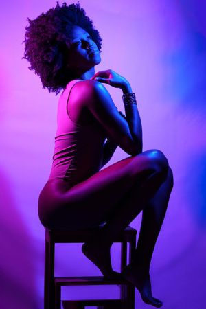 Seated female in vest in purple studio shot