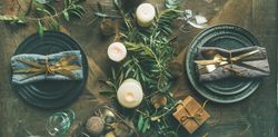 Festival holiday table setting on wooden table, with gold ornaments and branches, wide composition