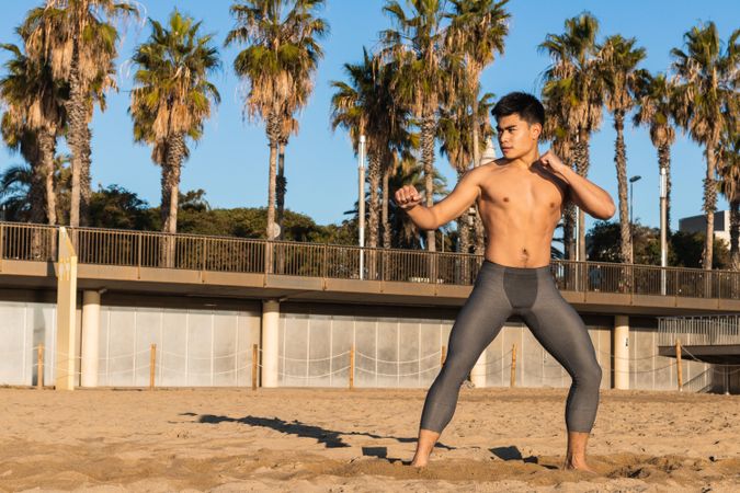 Athletic man in boxing stance training on beach