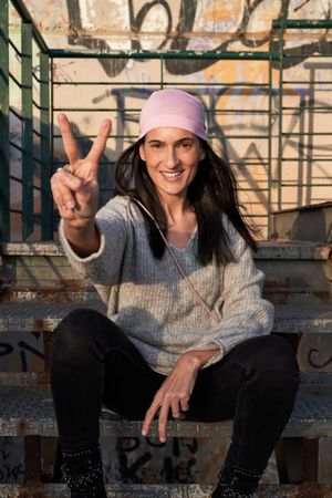 Positive woman in pink scarf showing v gesture