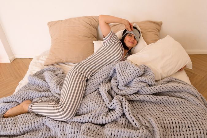 Woman stretching in bed with a joyful expression.