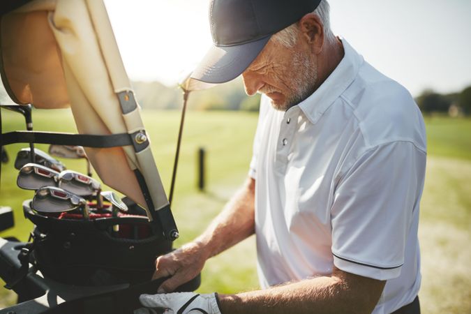 Man securing golf clubs in cart