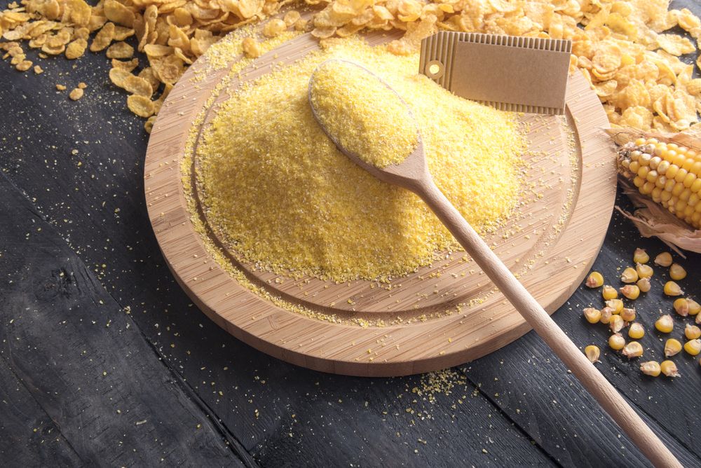 Pile of cornmeal on wooden plate with a wooden spoon and blank label