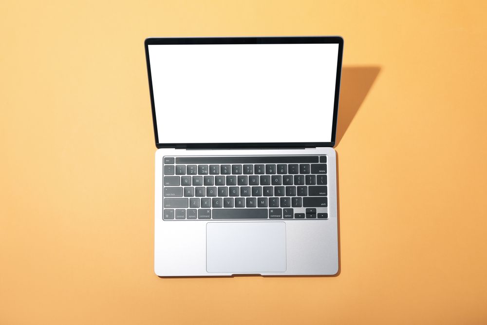 Top view of laptop with mockup screen on light orange desk