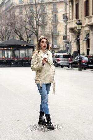 Portrait of young strolling in a city street, with takeaway coffee in hands
