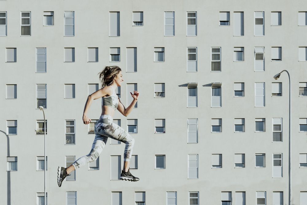 Woman in sportswear jumping near building