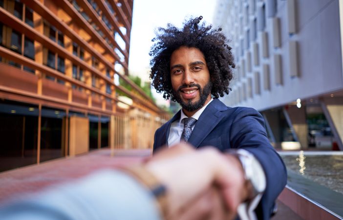 happy businessman shaking hands with partner and looking at camera