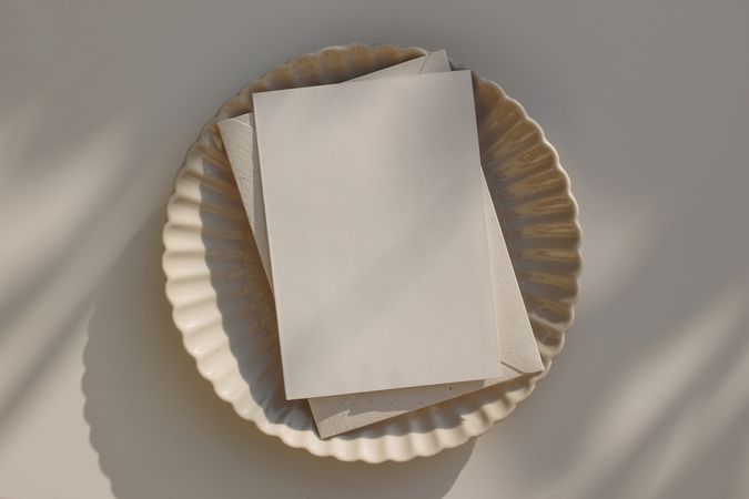 Blank vertical greeting card mockup with beige envelope on plate