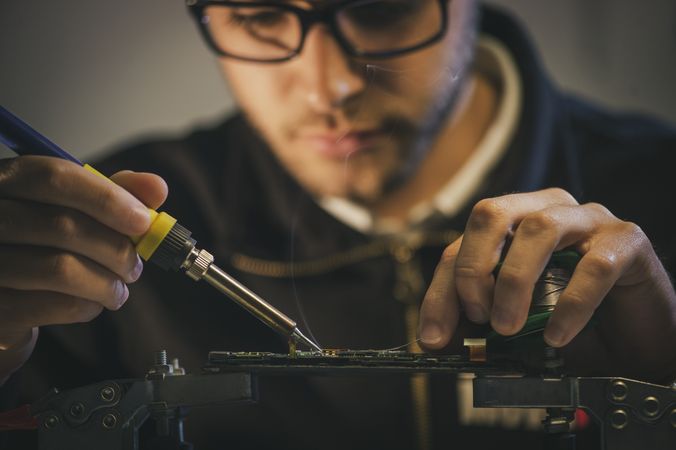 Crop man fixing microchip in workshop