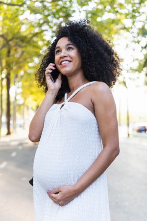 Smiling Black pregnant woman talking on smartphone