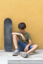 Front view of a young boy sitting on ground looking down 5r9Z72