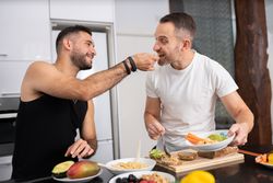 Male couple tasting meal as they prepare it