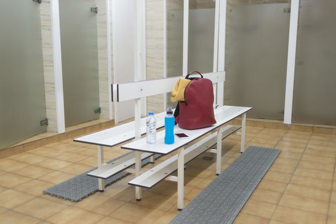 Empty shower room with backpack and drinks on bench