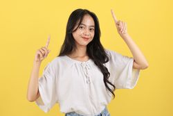 Portrait of Cheerful Asian Teenager with Long Hair and Casual Fashion, Pointing on Top for Advertisement