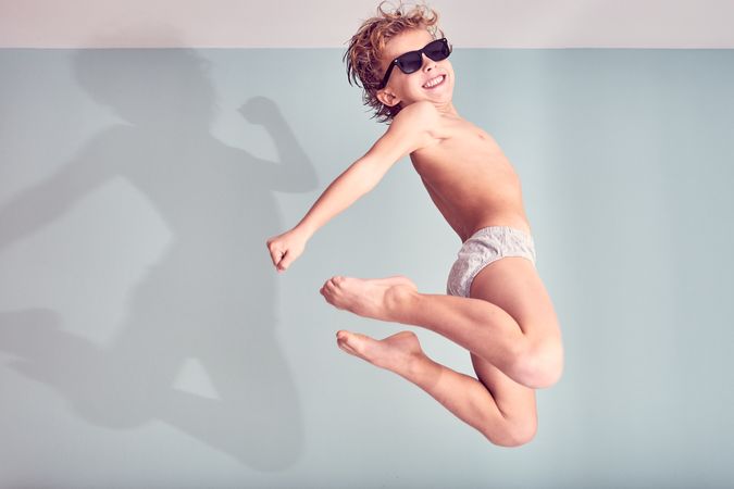 Excited boy in sunglasses jumping in air