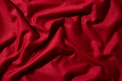 Crumpled wavy Red silky fabric background texture.