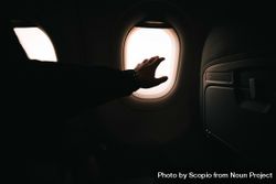 Person reaching out hand toward airplane window 48n6Y0