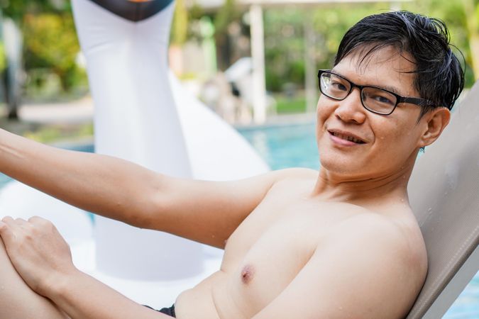 Smiling man in glasses relaxing by the pool