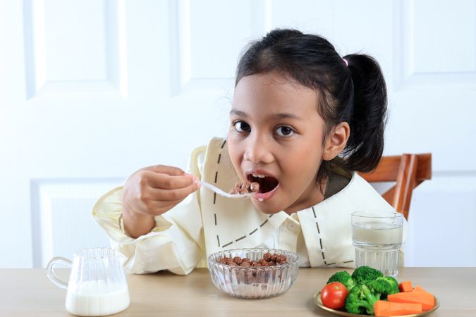 Cute Little Asian Girl Eating Chocolate Cereal